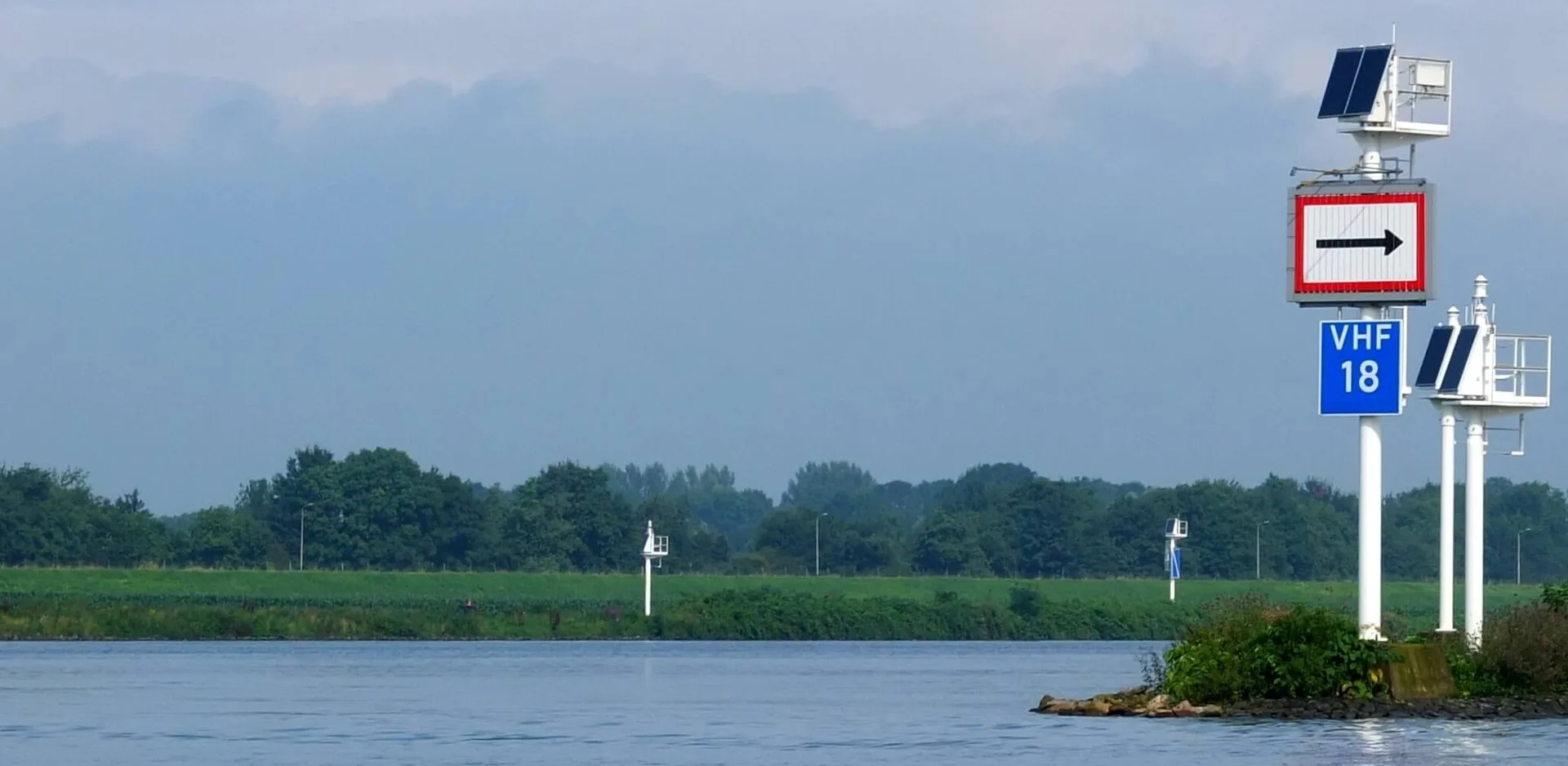 Nederlandse vaarweg met betonning en kilometerbord langs de oever